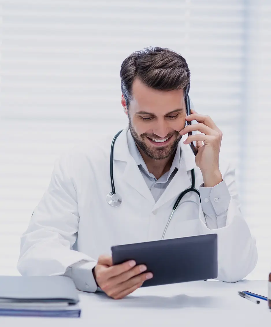male-doctor-talking-mobile-phone-while-using-digital-tablet